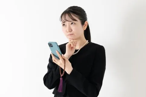 スマートフォンを片手に悩む女性