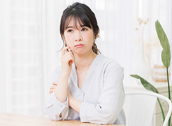 部屋で考え事をする若い女性