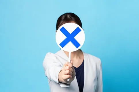 バツマークを持つ女性