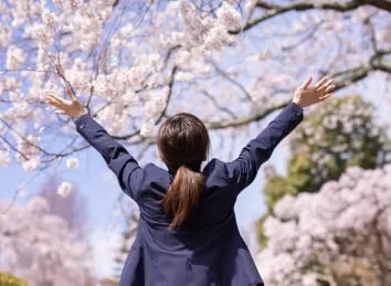 桜の下で万歳する生徒