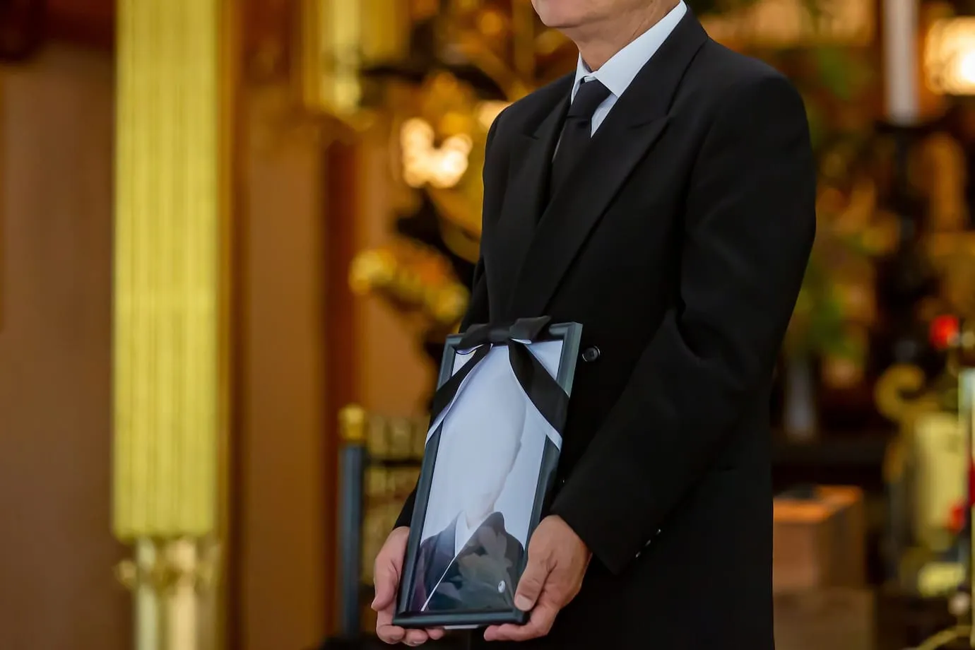 遺影を持つ男性